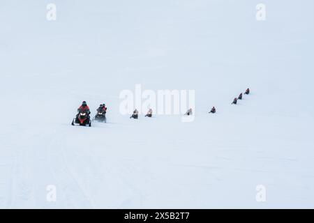 Gruppo di turisti in motoslitta sulla cima innevata del ghiacciaio dell'Islanda Foto Stock