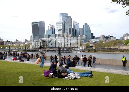 Persone turisti che si rilassano sul prato erboso vicino al Tower Bridge, vista della City of London dei grattacieli da More London Riverside nella primavera 2024 UK KATHY DEWITT Foto Stock
