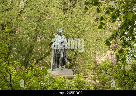 Staue di bronzo dello scrittore Esaias Tegnér in un fogliame verde a Lundagård, Lund, Svezia, 6 maggio 2024 Foto Stock