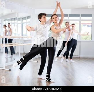 Giovane ballerina di balletto che sostiene la partner femminile in movimenti impegnativi Foto Stock