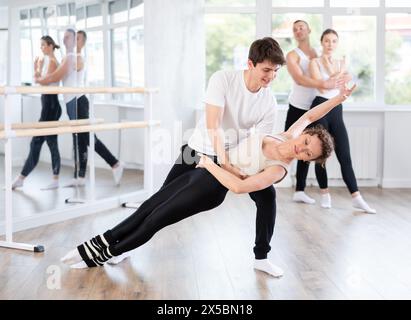 Giovane ballerina di balletto che sostiene la partner femminile in movimenti impegnativi Foto Stock