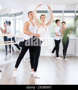 Felice coppia di balletti partner che si preparano alle prove per il concorso, addestrano le pose di balletto con supporto in classe Foto Stock