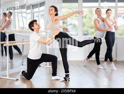 Felice coppia di balletti partner che si preparano alle prove per il concorso, addestrano le pose di balletto con supporto in classe Foto Stock