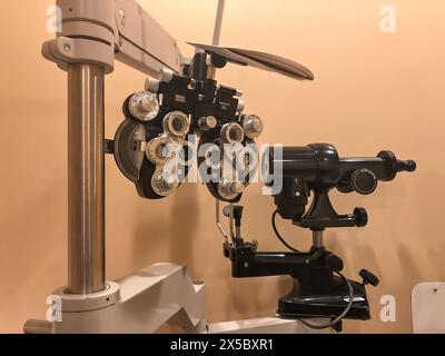 Primo piano di un phoropter in uno studio di medici oculistici con una tipica illuminazione silenziata. Foto Stock