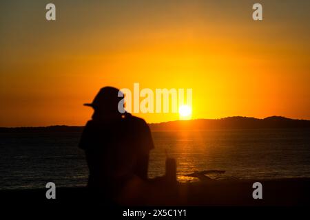 Salvador, Bahia, Brasile - 31 maggio 2019: Sagoma di una persona non identificata che si gode il drammatico tramonto a Praia da barra nella città di Salvador, B. Foto Stock