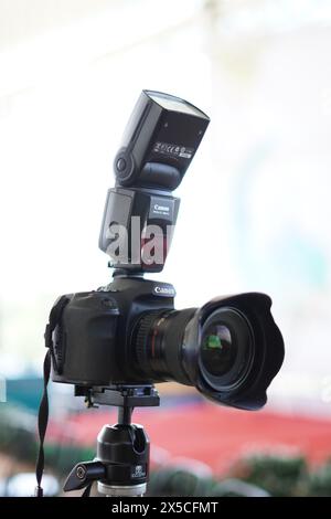 Fotocamera DSLR Canon nera montata su un cavalletto con flash esterno pronto all'uso Foto Stock
