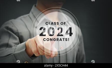 La mano del giovane preme un ologramma con le parole classe 2024. Congratulazioni. Foto Stock