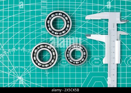 Misurare la pinza e i cuscinetti a rulli sul tappeto da taglio verde con spazio libero per copiare. Ingegneria meccanica e industria automobilistica Foto Stock