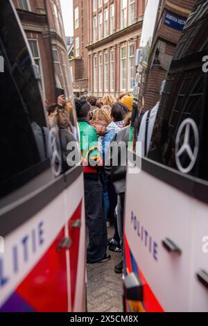 I manifestanti scorrono nelle viuzze davanti ai furgoni della polizia dopo che la polizia ha attraversato le barricate per porre fine a un'occupazione studentesca pro-Palestina presso l'Università di Amsterdam. La polizia smantellò una protesta e un'occupazione studentesca pro-Palestina presso l'Università di Amsterdam, impiegando mangoni, scudi e attrezzature per il movimento terra. Il confronto è seguito quando i manifestanti si sono radunati per la solidarietà palestinese tra le tensioni, le forze dell'ordine sono intervenute per disperdere la folla, con conseguenti scontri e arresti. (Foto di Michael Currie/SOPA Images/Sipa USA) Foto Stock