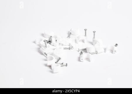 Chiodo per cavi, clip per cavi in plastica con chiodi in acciaio isolati su sfondo bianco Foto Stock