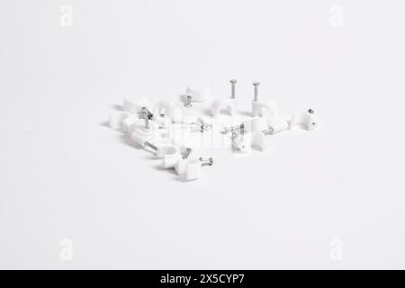 Chiodo per cavi, clip per cavi in plastica con chiodi in acciaio isolati su sfondo bianco Foto Stock