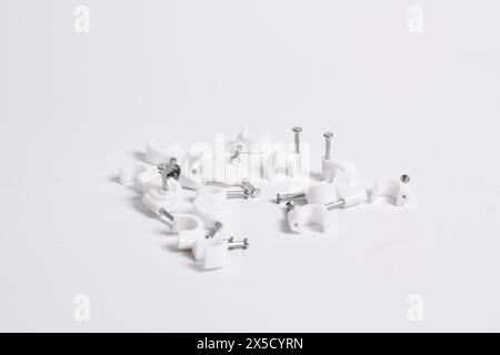 Chiodo per cavi, clip per cavi in plastica con chiodi in acciaio isolati su sfondo bianco Foto Stock