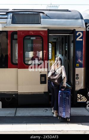 Essen, Germania - 5 giugno 2023: Una ragazza irriconoscibile con una valigia che entra nella carrozza ferroviaria alla stazione ferroviaria di Essen nel Nord Reno-Westphal Foto Stock