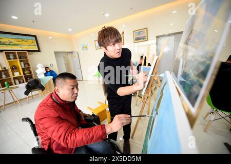 Yinchuan. 3 dicembre 2018. Questa foto scattata il 3 dicembre 2018 mostra Zuo Wenjun (fronte, R) che tutorizza un uomo disabile in pittura ad olio presso il centro di servizio di riabilitazione di Ningxia per persone con disabilità a Yinchuan, nella regione autonoma Ningxia Hui della Cina nord-occidentale. PER ANDARE CON "profilo: Il giovane cinese sfidato con un'opera d'arte esposta al Louvre" credito: Feng Kaihua/Xinhua/Alamy Live News Foto Stock