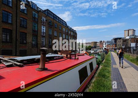 Londra - 06 04 2022: Ragazza che corre lungo il Regent's Canal con persone che camminano e case galleggianti ormeggiate Foto Stock