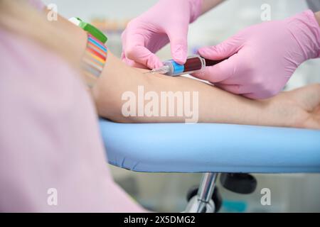 Primo piano operatore medico che aspira sangue dalla vena del cliente usando Vacutainer Foto Stock
