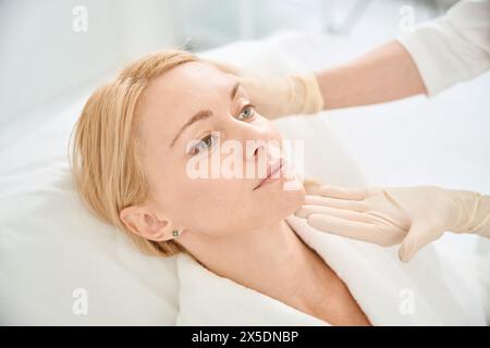 Estetista qualificato che guarda il viso di una donna adulta e controlla lo stato della pelle Foto Stock