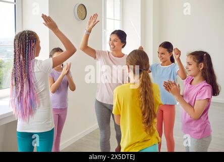 Felice insegnante di danza che dà cinque alti ai suoi figli alla fine della lezione in studio di coreografia. Foto Stock