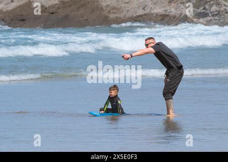 Un padre che aiuta suo figlio ad usare un body boogie board a Fistral Beach a Newquay in Cornovaglia nel Regno Unito. Foto Stock