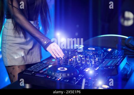 DJ ragazza che suona musica con giradischi e mixer sul palco nel night club Foto Stock