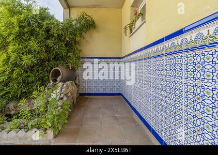Casa semi-indipendente con pavimenti in terracotta con piastrelle in stile spagnolo al centro del muro e un'area in vaso con molte piante Foto Stock