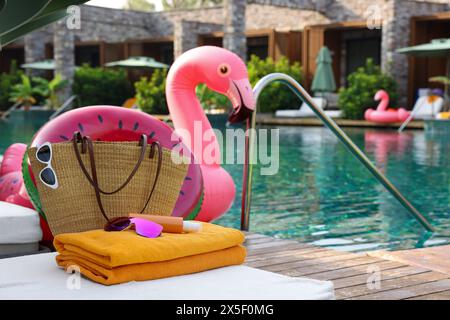 Accessori da spiaggia su sdraio, anello gonfiabile e galleggiante vicino alla piscina all'aperto, spazio per testo. Resort di lusso Foto Stock