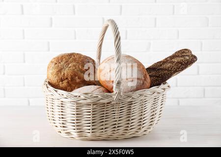 Diversi tipi di pane nel cestello in vimini su un tavolo di legno bianco Foto Stock