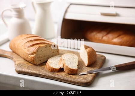 Cestino di pane in legno con pane appena sfornato su un tavolo in marmo bianco in cucina Foto Stock