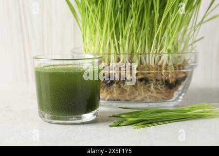 Bere erba di grano in vetro e germogli freschi su un tavolo leggero Foto Stock