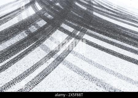 Un primo piano in bianco e nero di una pista di pneumatici su una strada innevata, che mostra schemi e texture distintivi lasciati dietro da un veicolo che passa. Il Foto Stock