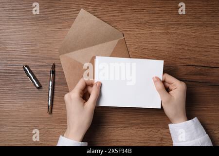 Donna con carta bianca al tavolo di legno, vista dall'alto. Spazio per il testo Foto Stock