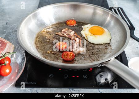 Colazione in padella. Deliziose uova strapazzate con pancetta e pomodori ciliegini. Foto di alta qualità Foto Stock