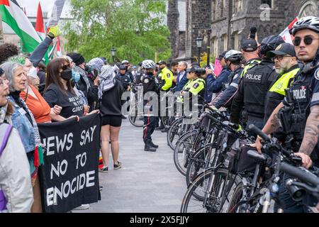 La polizia istituì una barricata umana con manifestanti pro-palestinesi e pro-Israele fuori dall'accampamento studentesco che occupava il King's College Circle presso l'U Foto Stock