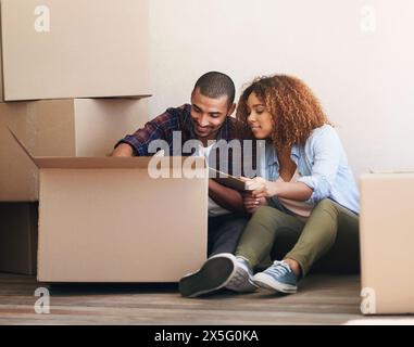 Nuova casa, scatole e coppia al piano, immobili e proprietà con pacchetto, spostamento e ricerca di articoli. Appartamento, uomo e donna a terra Foto Stock