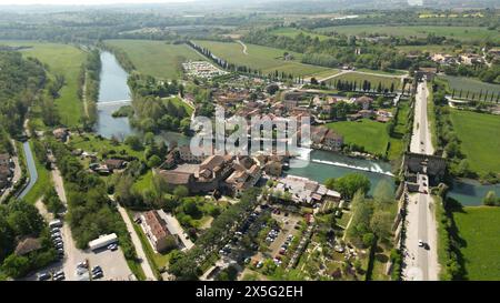 Bellissimo villaggio italiano sul fiume. Borghetto sul Mincio a sud del Lago di Garda, in Veneto. Riprese del drone del piccolo villaggio medievale Foto Stock