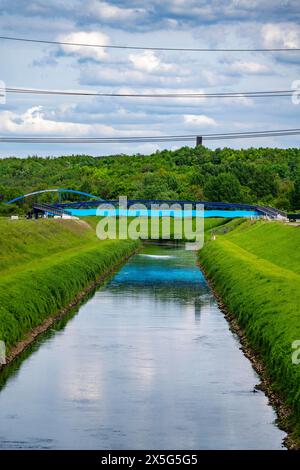 L'Emscher vicino a Essen-Karnap, con il cumulo di scorie di Schurenbach sullo sfondo, con il punto di riferimento di Bramme per la regione della Ruhr, Emscher Island Foot e. Foto Stock