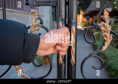 Mano di uomo che chiude il cancello. Foto Stock