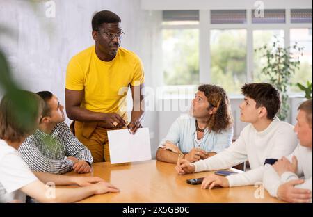 afroamericano che mostra documenti durante l'incontro con colleghi maschi Foto Stock