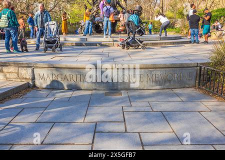 Vivace scena al Margarita Delacorte Memorial a Central Park, New York City, con diversi gruppi di persone che si divertono a divertirsi in un soleggiato Foto Stock