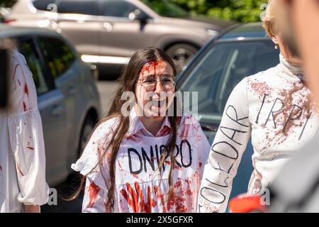 Una donna Ucraina che indossa un vestito con la parola DNIPRO scritta su di esso e dipinta con urla di sangue mentre l'ambasciatore russo posa fiori il giorno della vittoria sui nazisti al cimitero dei soldati sovietici attivisti ucraini protestano di fronte al cimitero dei soldati sovietici il giorno della vittoria sul nazismo. Donne ucraine vestite con abiti bianchi con città ucraine che sono state distrutte durante la guerra con la Russia scritto su di loro, questi abiti sono stati spalmati di sangue sintetico. Questo evento si è svolto il 9 maggio a Varsavia. (Foto di Marek Antoni Iwanczuk/SOPA Images/Sipa USA) Foto Stock