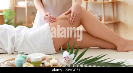 Bella giovane donna che riceve un massaggio scrub nel salone termale Foto Stock