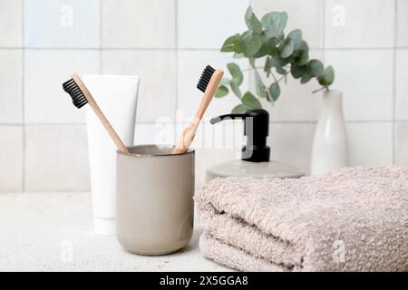 Set di articoli da bagno con spazzolini da denti sul tavolo contro le pareti di piastrelle leggere Foto Stock