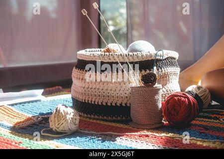 Primo piano di un cesto a maglia in cui sono presenti palline di lana multicolore Foto Stock