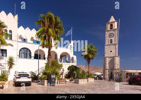 Storica torre dell'orologio e bandiera greca in una piazza sull'isola di Symi, in Grecia Foto Stock