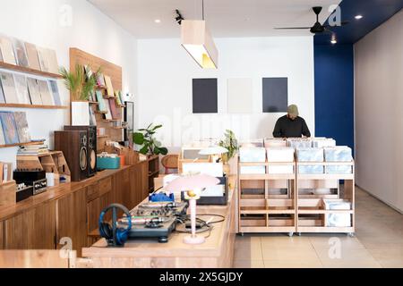 Un negozio accogliente dove un uomo in un berretto e barba sta in piedi e sceglie un disco in vinile. Foto Stock