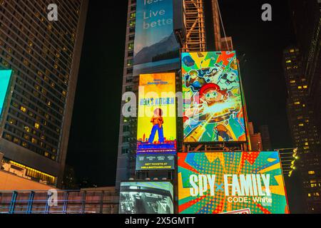 Vista notturna di Times Square a New York City, con cartelloni pubblicitari colorati e pubblicità per "Hell's Kitchen" e "Spy x Family" sullo sfondo Foto Stock