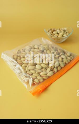 dadi di pistacchi in un sacchetto di plastica su sfondo colorato Foto Stock
