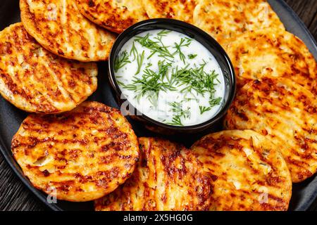 cottage al forno con parmigiano di formaggio fresco ad alto contenuto proteico e frittelle di aneto sul piatto con panna acida, vista sull'angolo olandese, primo piano Foto Stock