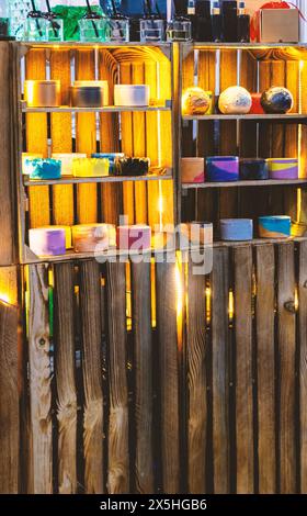 Uno scaffale pieno di contenitori di diversi colori con candele profumate e cosmetici. I contenitori sono disposti su un ripiano in fila. Lo scaffale è fatto Foto Stock