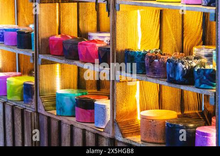 Uno scaffale pieno di contenitori di diversi colori con candele profumate e cosmetici. I contenitori sono disposti su un ripiano in fila. Lo scaffale è fatto Foto Stock